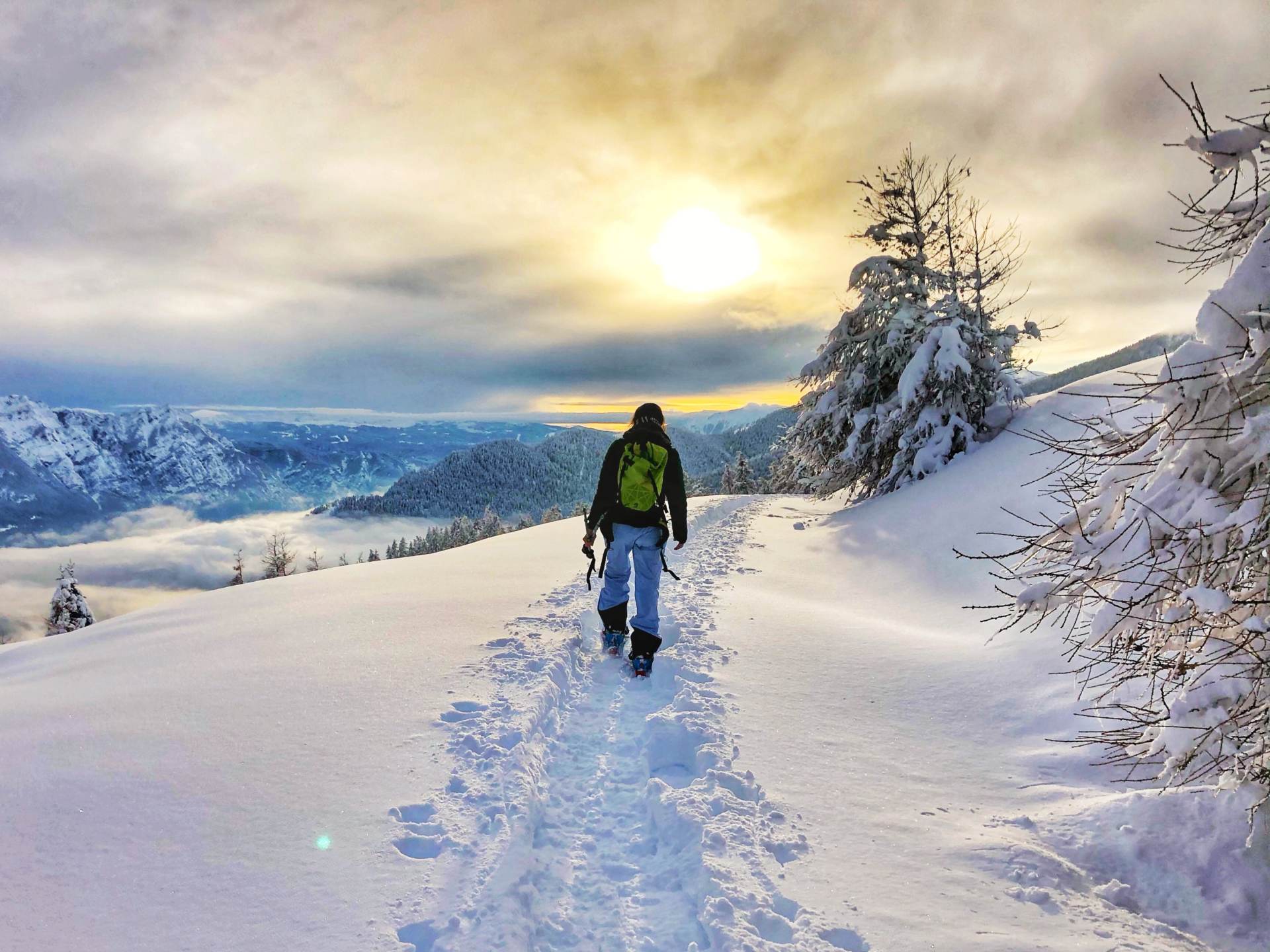 Escursionista con zaino sulla neve al tramonto
